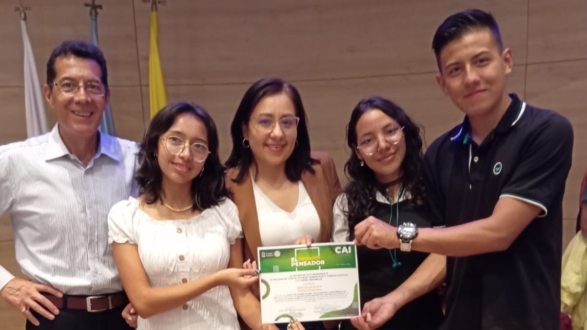 Estudiantes sosteniendo publicidad Evento el pensador