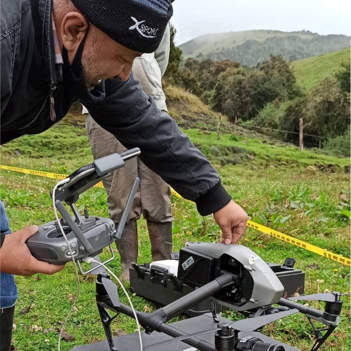 Persona preparando un dron en campo abierto