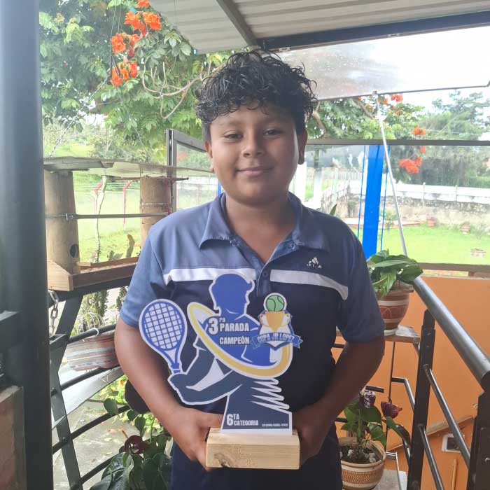 Fotografía de estudiante de tenis sosteniendo reconocimiento