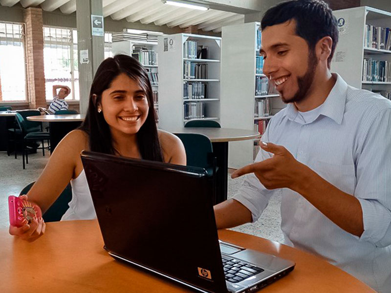 Foto Dos estudiantes sonriendo a un computador