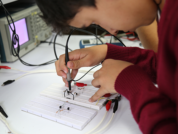 Imagen de joven realizando un circuito en una protoboard